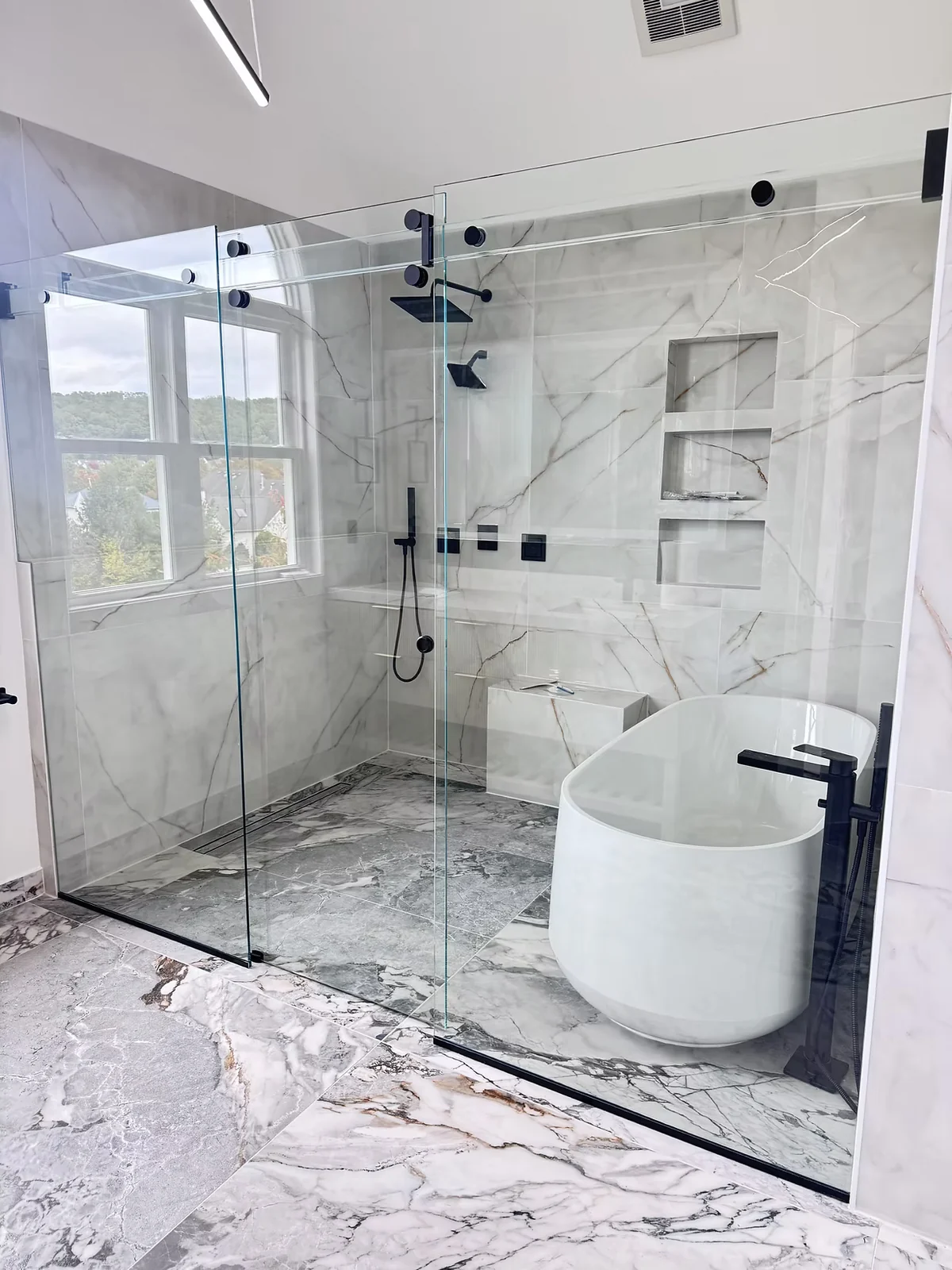 Titan Phantom sliding shower enclosure with a glass header and dark hardware beside a freestanding tub.