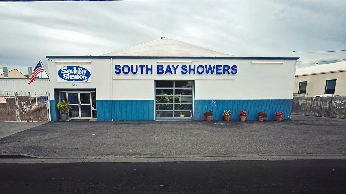 The white and blue South Bay Showers building at 1050 Martin Avenue, with the front entrance and company sign.