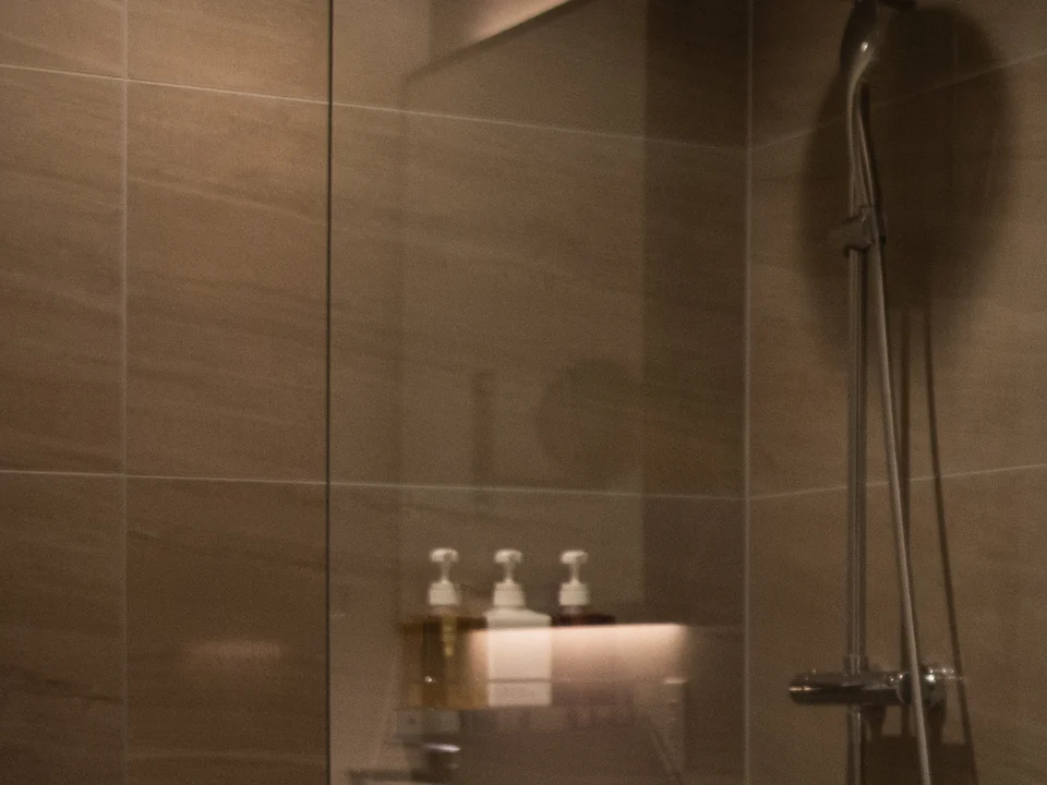 Close-up of the clear glass and warm tile in the pictured frameless shower.