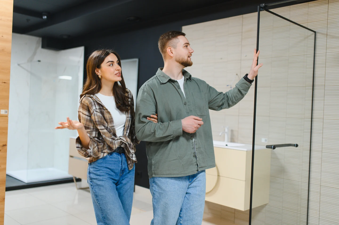 Two people comparing a glass shower door in a bathroom display.